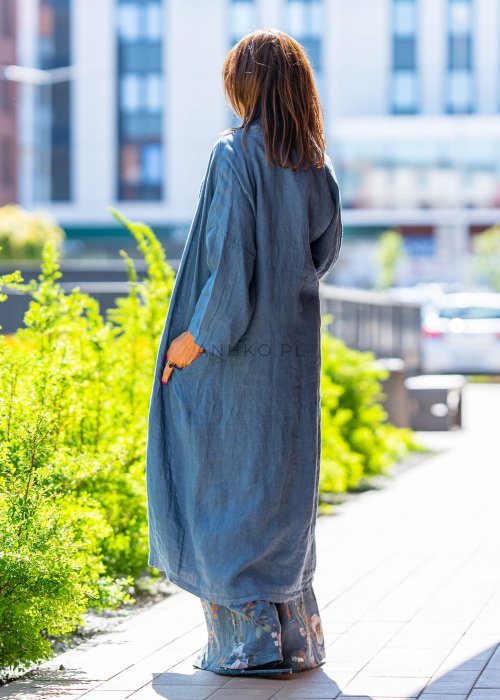 Długie niebieskie kimono lniane oversize z szerokimi rękawami, noszone w stylizacji z jasnym topem i wzorzystymi spodniami. Lekka, maxi narzutka w miejskim looku.