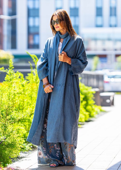 Długie niebieskie kimono lniane oversize z szerokimi rękawami, noszone w stylizacji z jasnym topem i wzorzystymi spodniami. Lekka, maxi narzutka w miejskim looku.