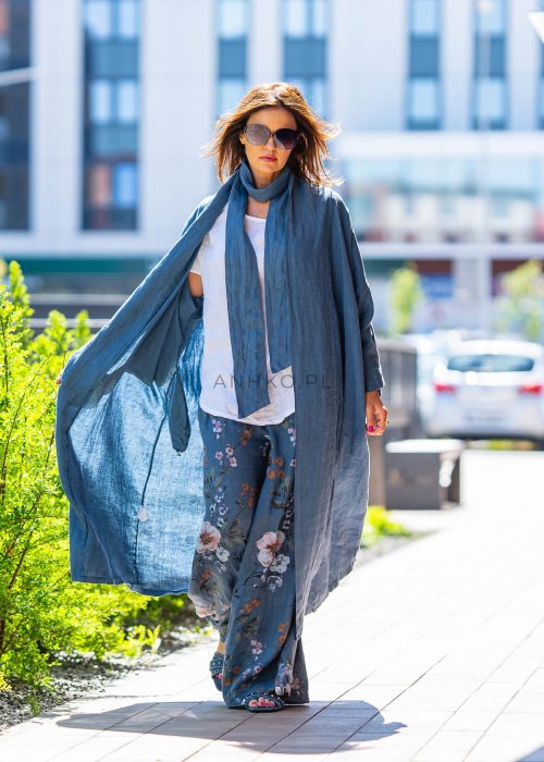 Długie niebieskie kimono lniane oversize z szerokimi rękawami, noszone w stylizacji z jasnym topem i wzorzystymi spodniami. Lekka, maxi narzutka w miejskim looku.