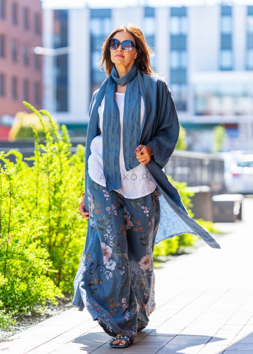 Długie niebieskie kimono lniane oversize z szerokimi rękawami, noszone w stylizacji z jasnym topem i wzorzystymi spodniami. Lekka, maxi narzutka w miejskim looku.