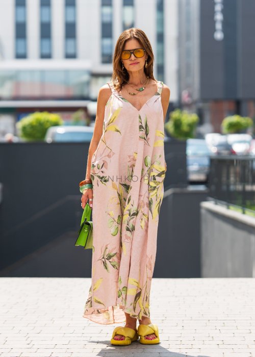 Jasnoróżowa damska sukienka lniana maxi z roślinnym printem i marszczonymi ramiączkami. Lekka, luźna forma z kieszeniami, prezentowana w miejskiej stylizacji.