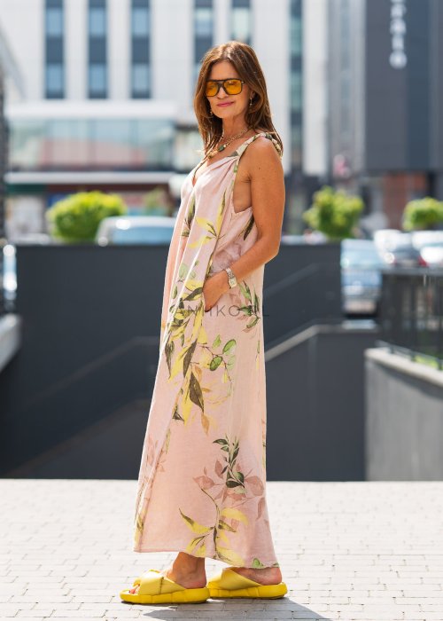 Jasnoróżowa damska sukienka lniana maxi z roślinnym printem i marszczonymi ramiączkami. Lekka, luźna forma z kieszeniami, prezentowana w miejskiej stylizacji.