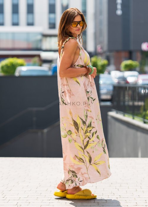 Jasnoróżowa damska sukienka lniana maxi z roślinnym printem i marszczonymi ramiączkami. Lekka, luźna forma z kieszeniami, prezentowana w miejskiej stylizacji.