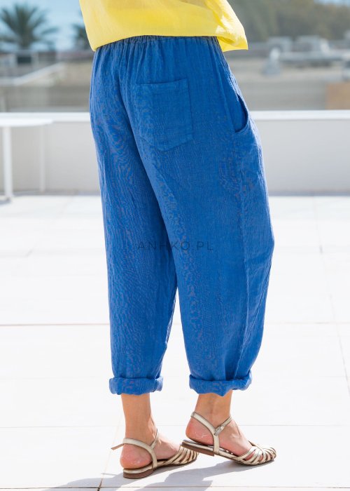 Chabrowe spodnie lniane damskie z elastycznym pasem i podwiniętą nogawką, zestawione z lekką żółtą bluzką w swobodnej stylizacji.