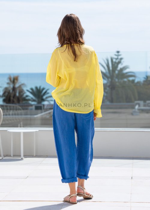 Chabrowe spodnie lniane damskie z elastycznym pasem i podwiniętą nogawką, zestawione z lekką żółtą bluzką w swobodnej stylizacji.