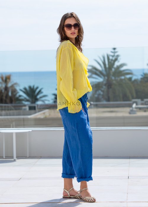 Chabrowe spodnie lniane damskie z elastycznym pasem i podwiniętą nogawką, zestawione z lekką żółtą bluzką w swobodnej stylizacji.