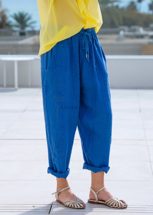 Chabrowe spodnie lniane damskie z elastycznym pasem i podwiniętą nogawką, zestawione z lekką żółtą bluzką w swobodnej stylizacji.