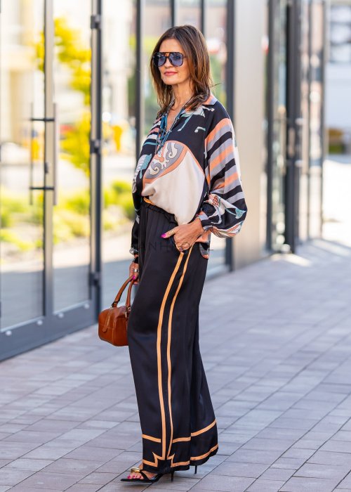 Czarne spodnie damskie z szeroką nogawką i elastyczną talią, ozdobione kontrastowymi brzoskwiniowymi lampasami.