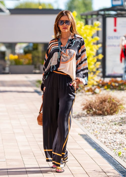 Czarne spodnie damskie z szeroką nogawką i elastyczną talią, ozdobione kontrastowymi brzoskwiniowymi lampasami.