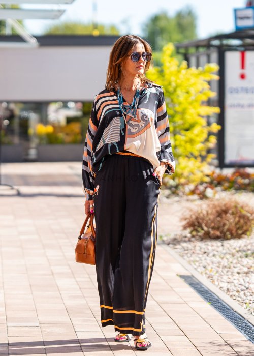 Czarne spodnie damskie z szeroką nogawką i elastyczną talią, ozdobione kontrastowymi brzoskwiniowymi lampasami.