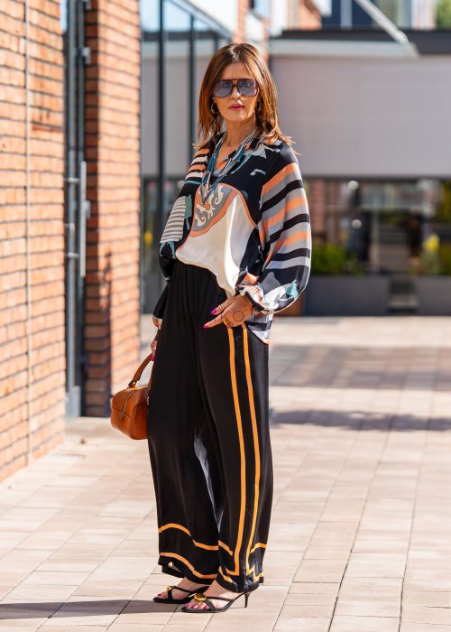 Czarne spodnie damskie z szeroką nogawką i elastyczną talią, ozdobione kontrastowymi brzoskwiniowymi lampasami.