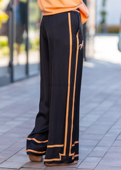 Czarne spodnie damskie z szeroką nogawką i elastyczną talią, ozdobione kontrastowymi brzoskwiniowymi lampasami.