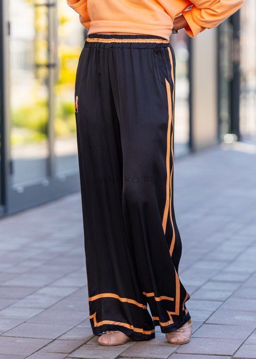 Czarne spodnie damskie z szeroką nogawką i elastyczną talią, ozdobione kontrastowymi brzoskwiniowymi lampasami.