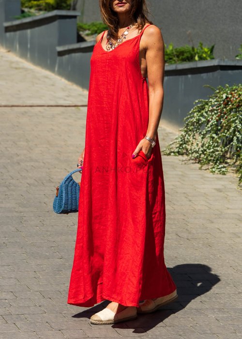 Czerwona lniana sukienka maxi na ramiączkach o luźnym kroju, stylizacja z plecioną torebką i biżuterią w miejskim stylu.