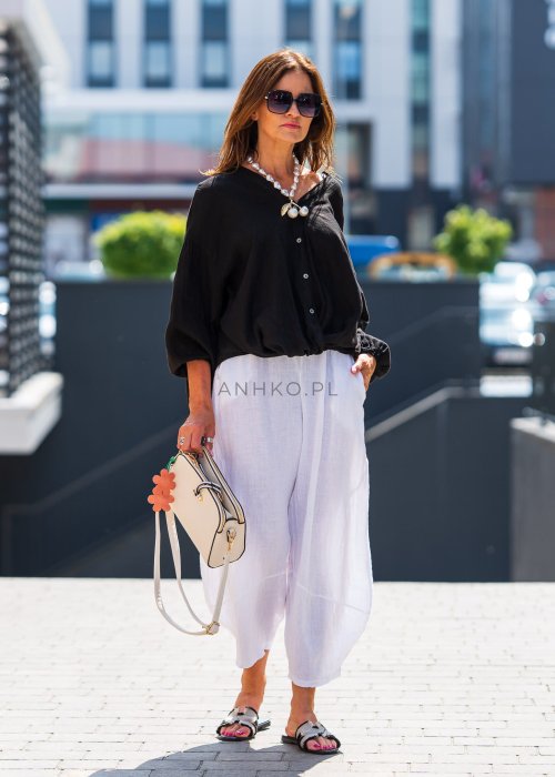 Czarna lniana koszula damska oversize z dekoltem V i guzikami, zestawiona z jasnymi spodniami w eleganckiej, miejskiej stylizacji.