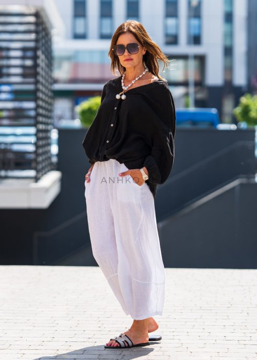 Czarna lniana koszula damska oversize z dekoltem V i guzikami, zestawiona z jasnymi spodniami w eleganckiej, miejskiej stylizacji.