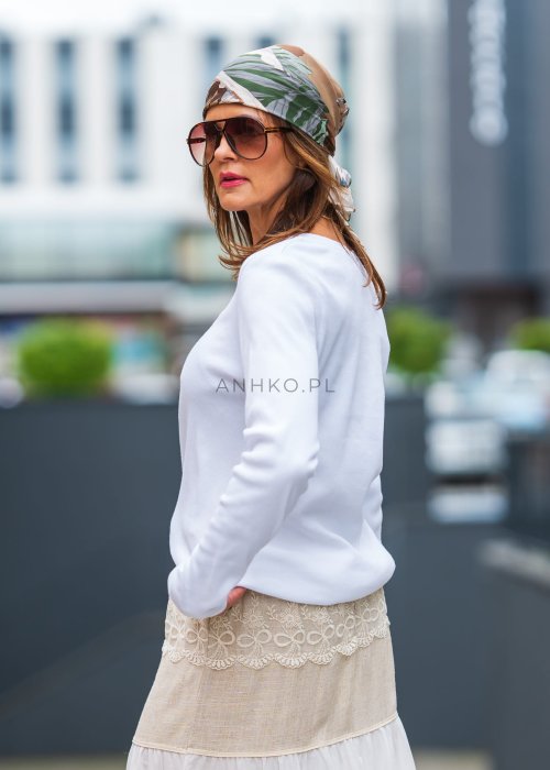 Biała prążkowana bluzka damska z długim rękawem i dekoltem zapinanym na guziki, zestawiona z jasną spódnicą w miejskiej stylizacji.