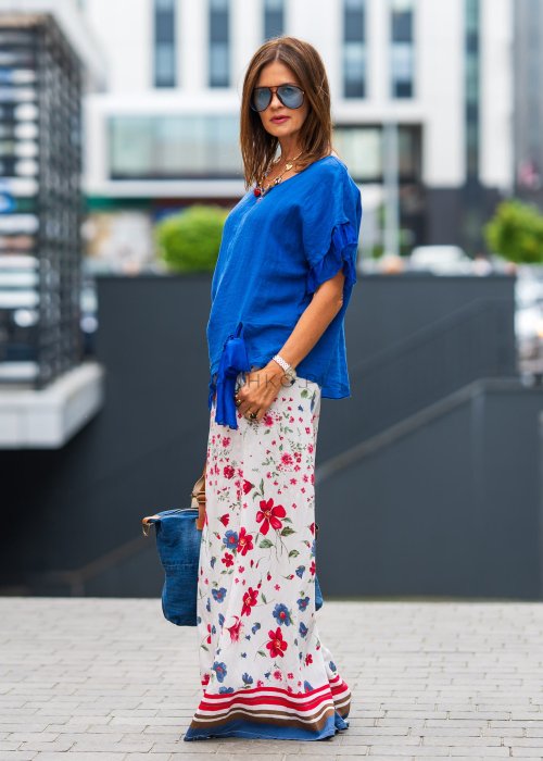 Chabrowa lniana bluzka damska z dodatkiem jedwabiu, falbaniastymi rękawami i asymetrycznym wykończeniem z ozdobnym wiązaniem. Stylowy model do codziennych i eleganckich stylizacji.