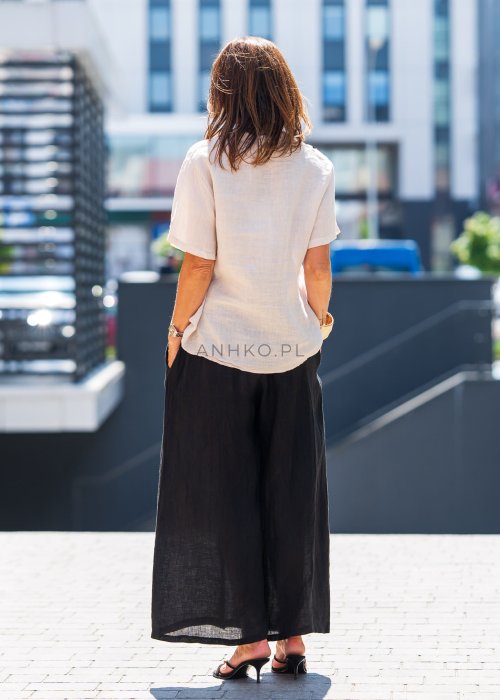 Beżowa bluzka lniana z krótkim rękawem i czarnym, artystycznym haftem na przodzie. Stylizacja z czarną spódnicą maxi i minimalistyczną biżuterią.