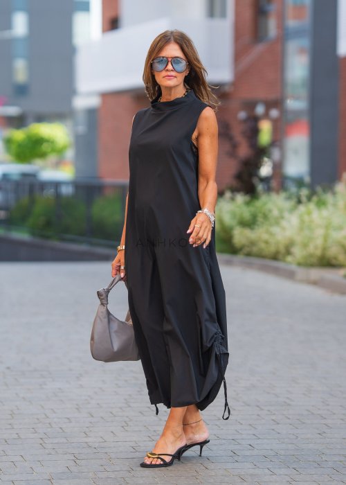 Sukienka-ShapeMe-Czarna (5).jpgCzarna sukienka maxi bez rękawów ze stójką i regulowanym dołem na troczki. Modelka prezentuje minimalistyczną miejską stylizację z sandałami i torebką.