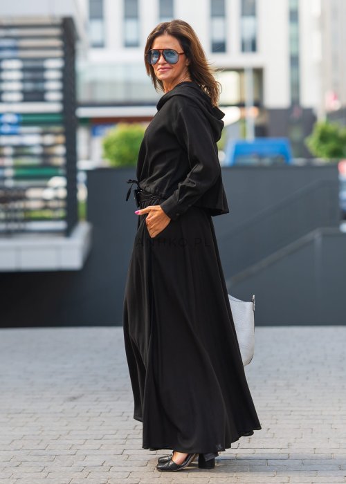 Czarny komplet z lekkiej, przewiewnej tkaniny – bluza z kapturem i wiązaniem w talii oraz długa, swobodna spódnica. Elegancja i wygoda w jednym.