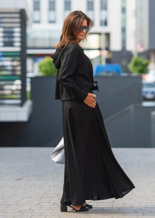 Czarny komplet z lekkiej, przewiewnej tkaniny – bluza z kapturem i wiązaniem w talii oraz długa, swobodna spódnica. Elegancja i wygoda w jednym.