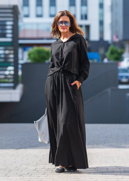 Czarny komplet z lekkiej, przewiewnej tkaniny – bluza z kapturem i wiązaniem w talii oraz długa, swobodna spódnica. Elegancja i wygoda w jednym.