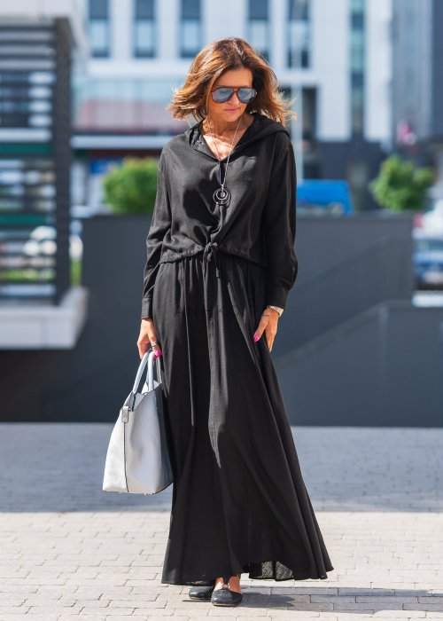 Czarny komplet z lekkiej, przewiewnej tkaniny – bluza z kapturem i wiązaniem w talii oraz długa, swobodna spódnica. Elegancja i wygoda w jednym.