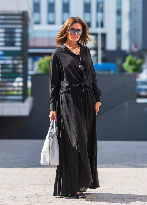 Czarny komplet z lekkiej, przewiewnej tkaniny – bluza z kapturem i wiązaniem w talii oraz długa, swobodna spódnica. Elegancja i wygoda w jednym.