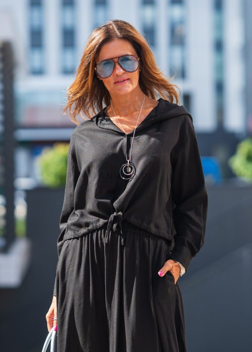 Czarny komplet z lekkiej, przewiewnej tkaniny – bluza z kapturem i wiązaniem w talii oraz długa, swobodna spódnica. Elegancja i wygoda w jednym.