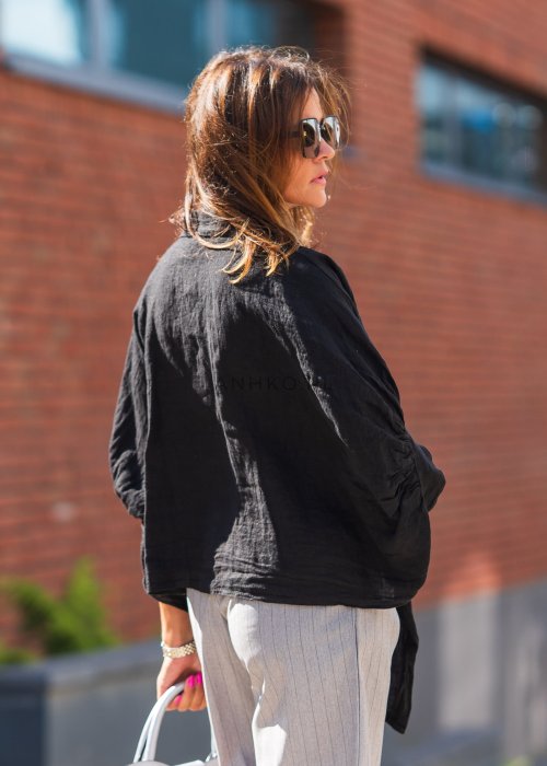 Czarna lniana koszula oversize z kołnierzykiem i wiązaniem z przodu, ozdobiona aplikacjami, zestawiona z jasnymi szortami w paski