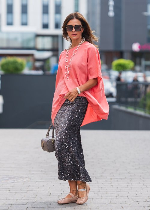 Bluzka damska oversize w kolorze koralowym, krótki rękaw, dekolt łódka, lekko asymetryczny krój, styl casual elegancki
