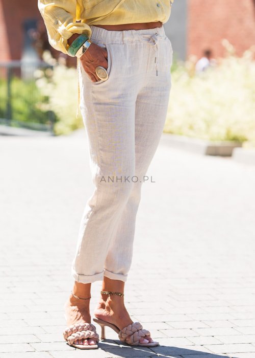 Jasne lniane spodnie damskie o zwężanym kroju, z elastyczną talią i troczkiem, w lekkim, letnim stylu casual