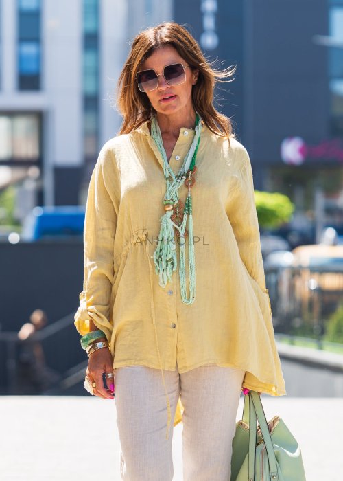 Żółta lniana koszula oversize z długim rękawem i kołnierzykiem, zapinana na guziki, w zestawie z jasnymi spodniami w stylu letnim