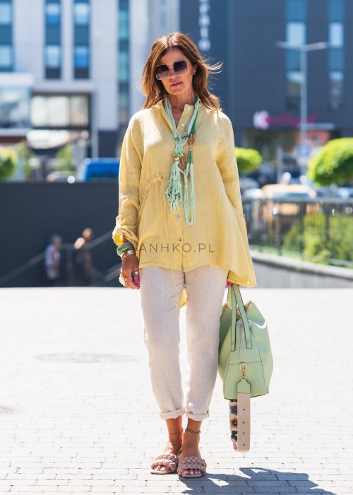 Żółta lniana koszula oversize z długim rękawem i kołnierzykiem, zapinana na guziki, w zestawie z jasnymi spodniami w stylu letnim