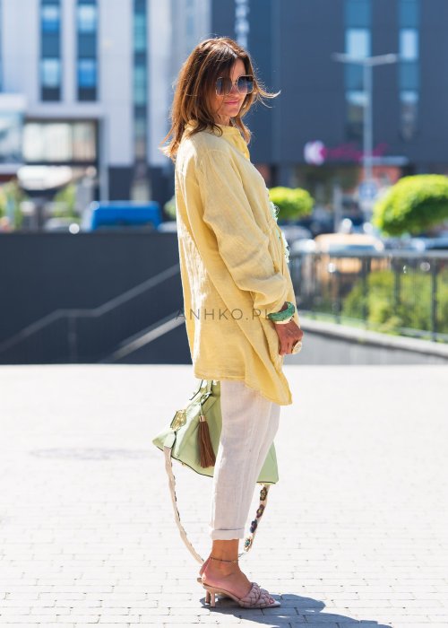 Żółta lniana koszula oversize z długim rękawem i kołnierzykiem, zapinana na guziki, w zestawie z jasnymi spodniami w stylu letnim