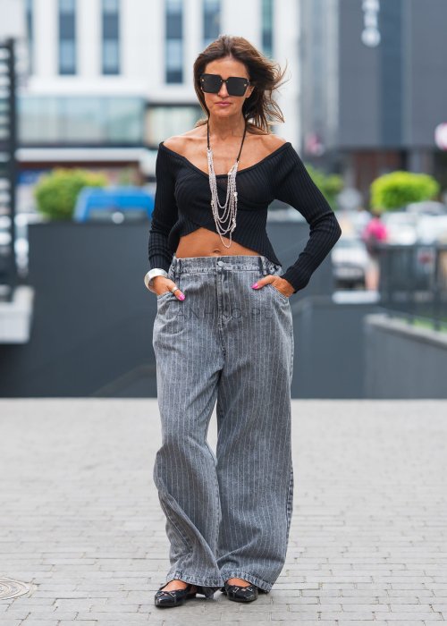 Czarny, prążkowany top z długim rękawem i dekoltem hiszpańskim, eksponującym ramiona. Krótki, asymetryczny krój dodaje mu zmysłowości i nowoczesnego charakteru.