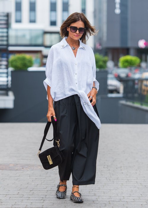Biała lniana koszula oversize z kołnierzykiem, ozdobnymi guzikami i wiązaniem z przodu, w zestawie z czarnymi spodniami