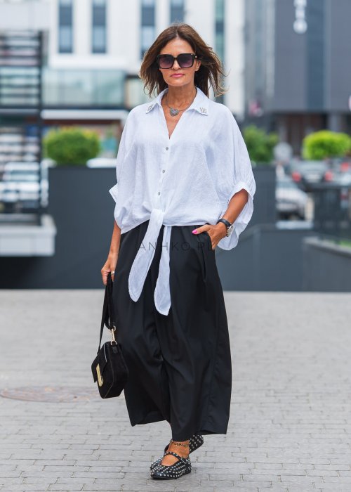 Biała lniana koszula oversize z kołnierzykiem, ozdobnymi guzikami i wiązaniem z przodu, w zestawie z czarnymi spodniami