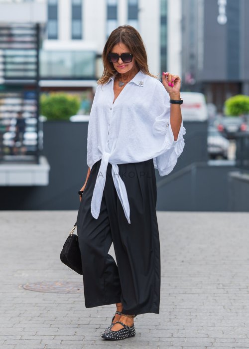 Biała lniana koszula oversize z kołnierzykiem, ozdobnymi guzikami i wiązaniem z przodu, w zestawie z czarnymi spodniami