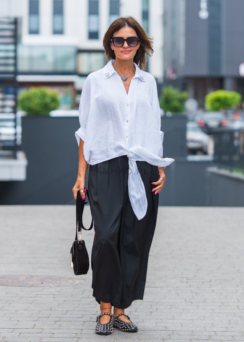 Biała lniana koszula oversize z kołnierzykiem, ozdobnymi guzikami i wiązaniem z przodu, w zestawie z czarnymi spodniami