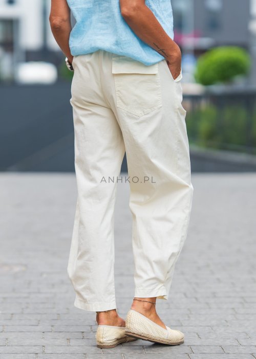 Jasnokremowe, luźne spodnie o prostym kroju, wykonane z lekkiego i przewiewnego materiału, z wygodną gumką w pasie i kieszeniami po bokach – idealne do letnich, swobodnych stylizacji.