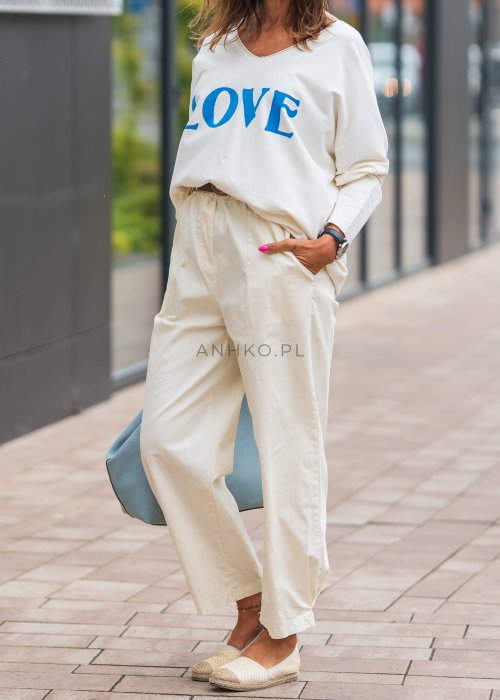 Jasnokremowe, luźne spodnie o prostym kroju, wykonane z lekkiego i przewiewnego materiału, z wygodną gumką w pasie i kieszeniami po bokach – idealne do letnich, swobodnych stylizacji.