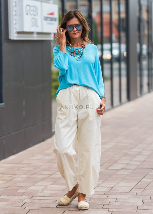 Jasnokremowe, luźne spodnie o prostym kroju, wykonane z lekkiego i przewiewnego materiału, z wygodną gumką w pasie i kieszeniami po bokach – idealne do letnich, swobodnych stylizacji.
