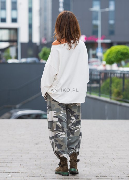 Biała bluzka oversize damska z szerokim dekoltem i haftowanym detalem na rękawie, zestawiona ze spodniami moro w casualowej stylizacji miejskiej.