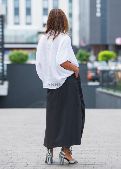 Biała, luźna koszula z kołnierzykiem, czarne spodnie z ozdobnym paskiem i długi naszyjnik z perełkami.