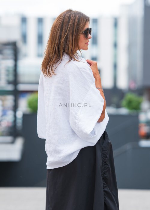 Biała, luźna koszula z kołnierzykiem, czarne spodnie z ozdobnym paskiem i długi naszyjnik z perełkami.