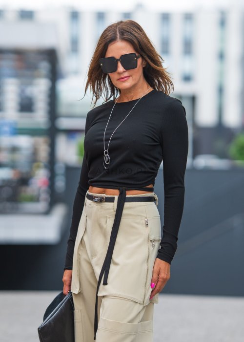 Czarny crop top z odkrytymi plecami i wiązaniem, zestawiony z beżowymi spodniami cargo, tworzy odważny, miejski look.