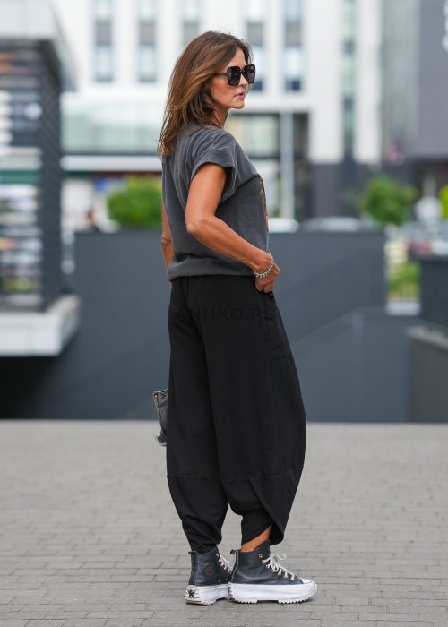 Czarne spodnie damskie o szerokim kroju typu bombka z dużymi kieszeniami i elastyczną talią. Stylizacja z t-shirtem i sneakersami w miejskim, casualowym wydaniu.