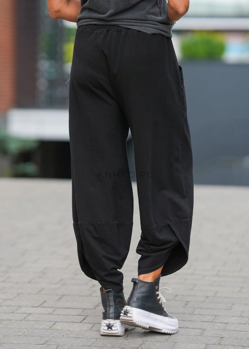 Czarne spodnie damskie o szerokim kroju typu bombka z dużymi kieszeniami i elastyczną talią. Stylizacja z t-shirtem i sneakersami w miejskim, casualowym wydaniu.